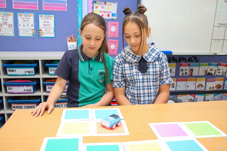 Two girls playing with an Indi robotic