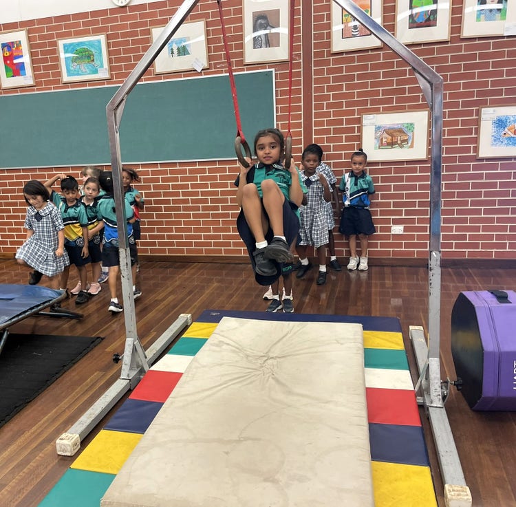 a girl using gymnastic equipment. she is swinging on rings