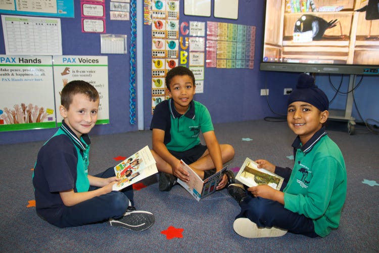 3 students sitting on the floor reading books