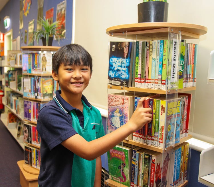 a boy looking at a selection of books in library