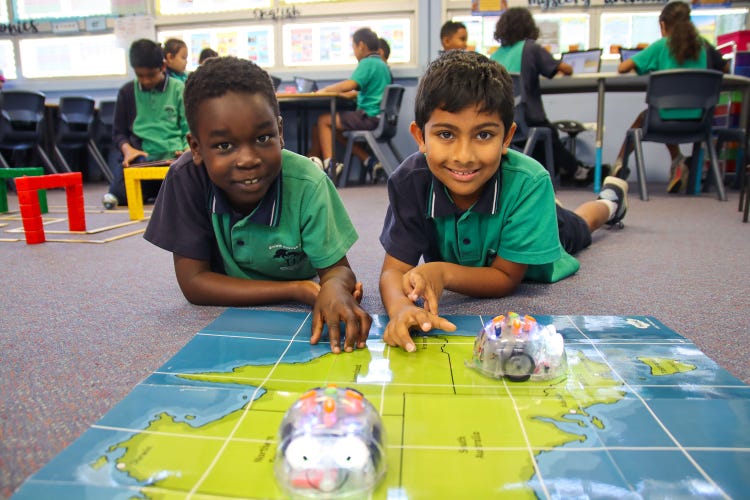 2 students playing with robotic Bee Bots