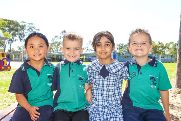 4 students sitting on a bench smiling