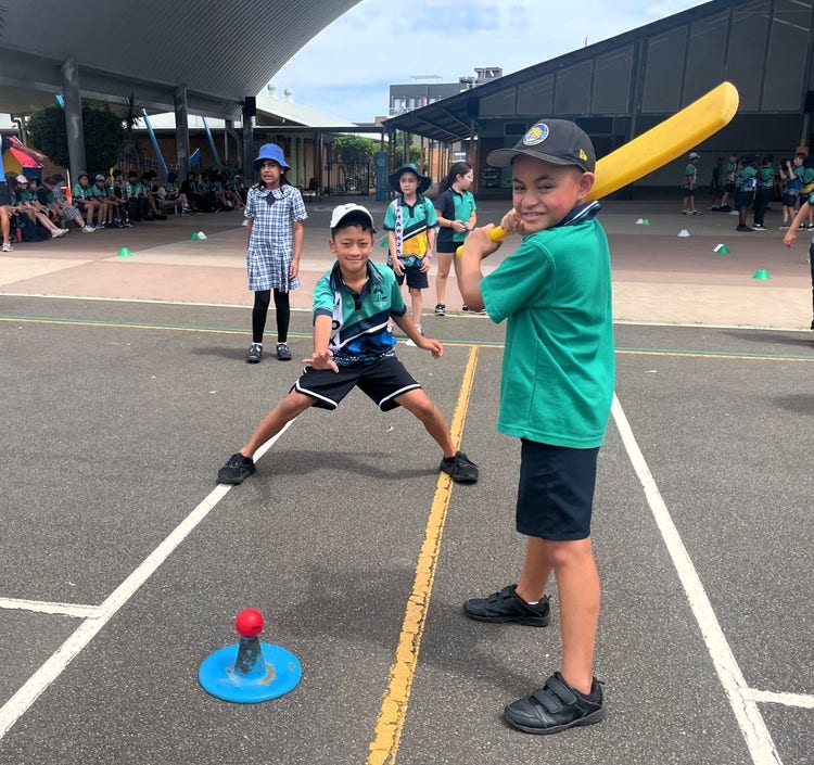 students playing a game of cricket. a boy is holding a bat ready to swing