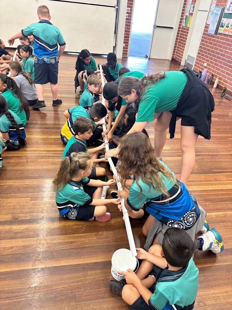 a group of students working together to make a long pole