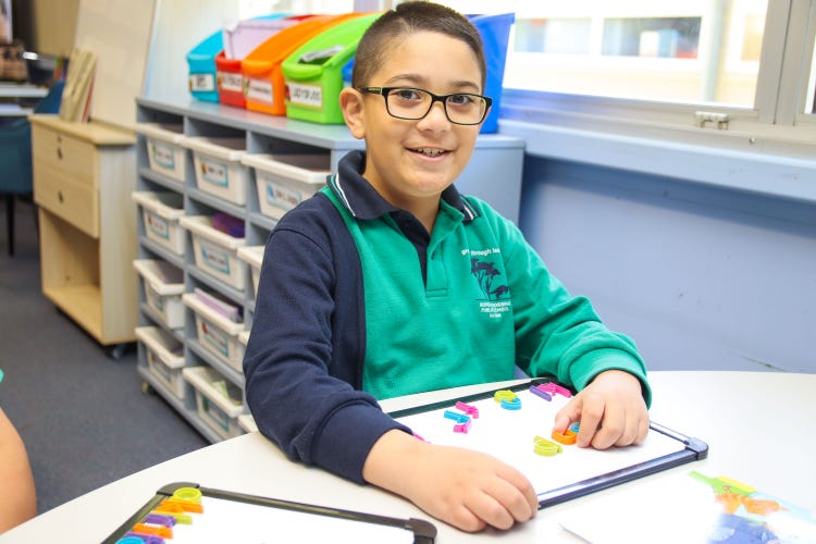 a boy sitting with a whiteboard and magnetic letters