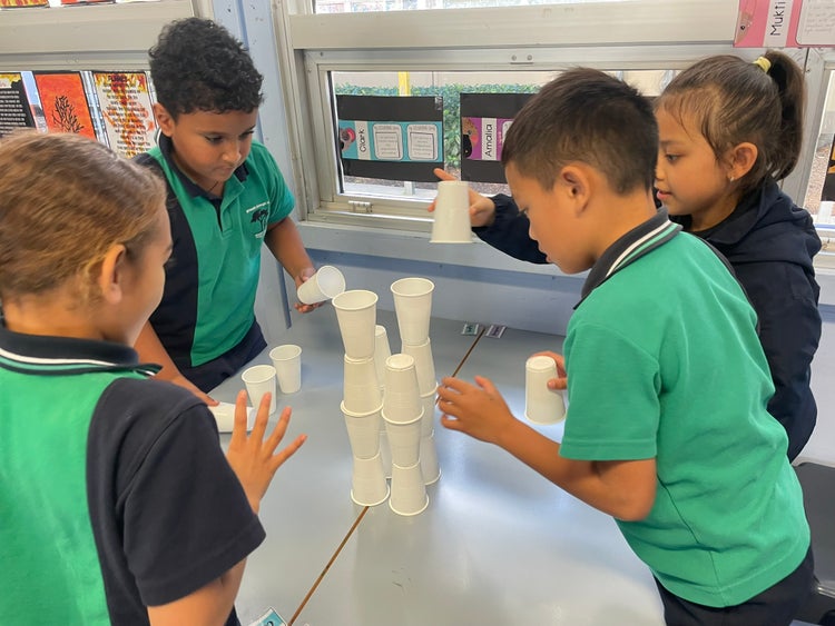4 students working together to make a tower using plastic cups