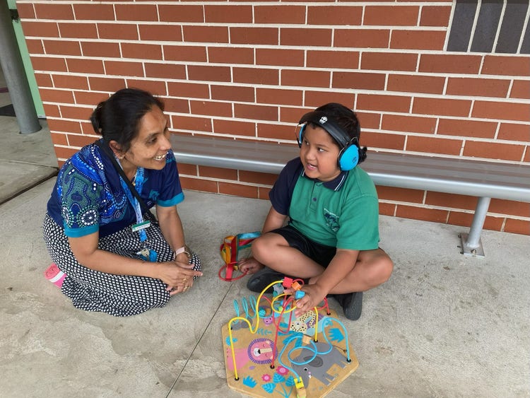 a teacher with a student sitting on the ground playing with a toy