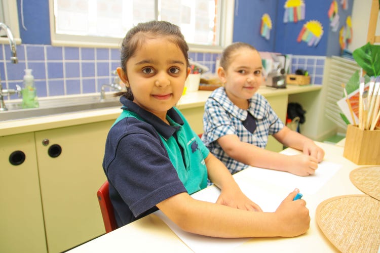 2 students drawing and looking at the camera