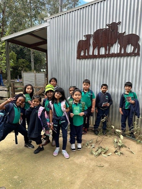 a group of students standing outside a shed at the farm