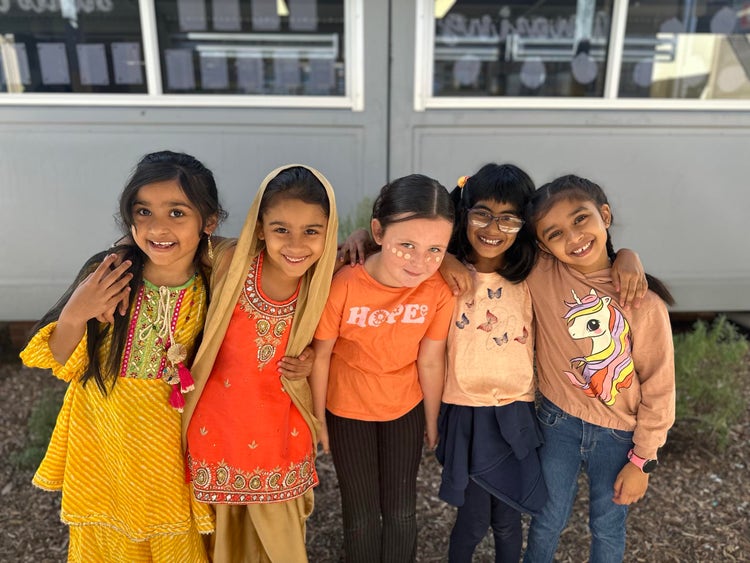 5 studetns dressed in orange and cultural clothes