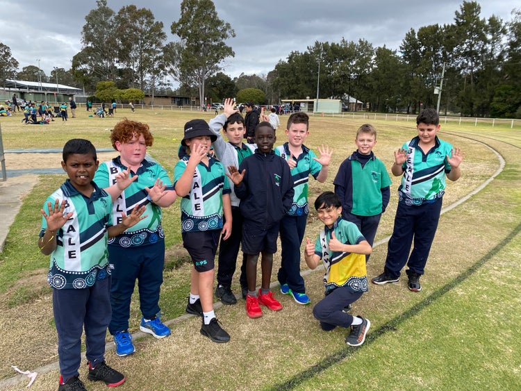 a group of boys standing on a sport field smiling