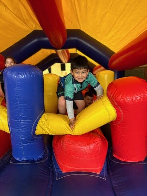 a boy climbing on an inflatable catsle