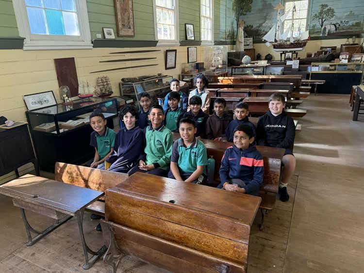 a group of boys sitting in an olden days style school with old furniture